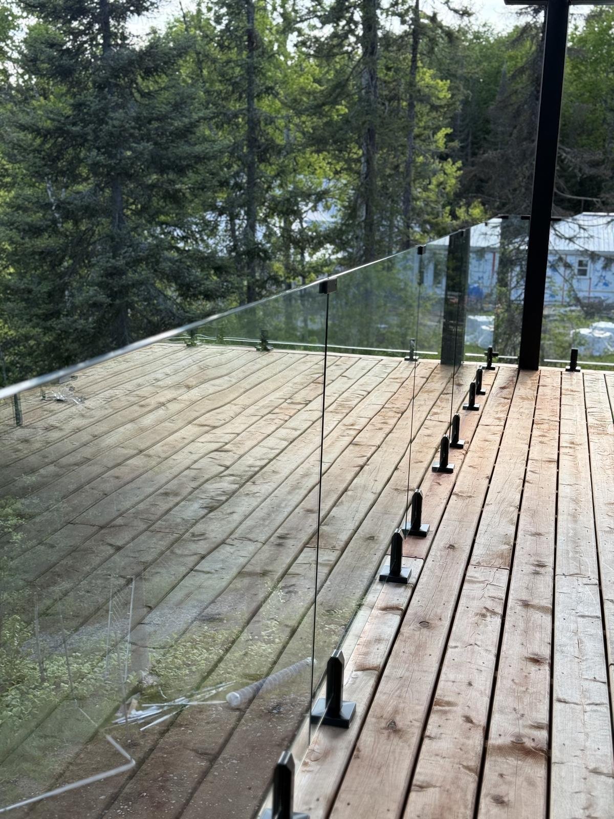 Glass railing on wood deck overlooking forest